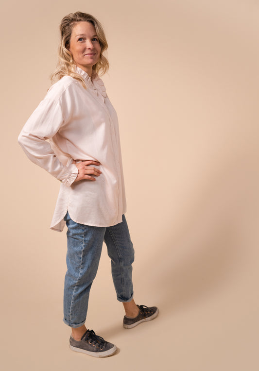Model image of the Ruffle blouse in oyster pink paired with mom jeans untucked